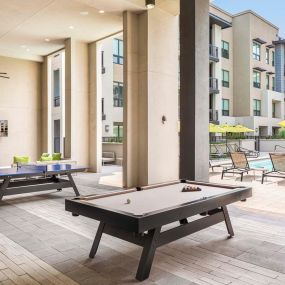 Covered poolside outdoor lounge with billiards ping pong and seating