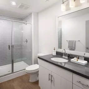 Bathroom with glass enclosed shower granite countertops and wood look flooring