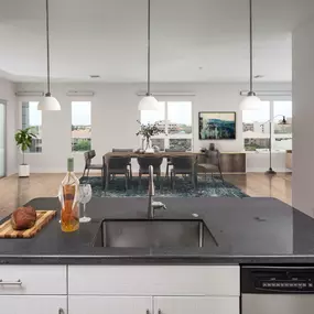 Penthouse kitchen with double ovens island with undermount sink and pendant lighting