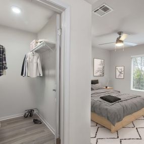 Bedroom with walk in closet wood look flooring and ceiling fan