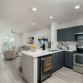 Open concept floor plan kitchen and living area with wood look floors french doors to private balcony and ceiling fan