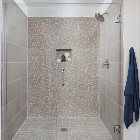 White contemporary walk-in shower with frameless glass door and geometric tile surround