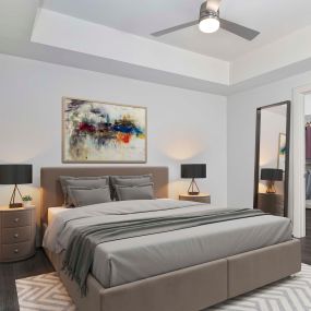 Modern gray bedroom with hardwood-style flooring, ceiling fan, and walk-in closet