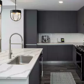 Modern gray kitchen with stainless steel appliances, gas stovetop, and large kitchen island