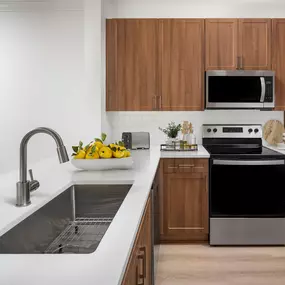 Kitchen with white quartz countertops, stainless steel appliances and a farmhouse sink at Camden Fair Lakes Apartments in Fairfax, VA.