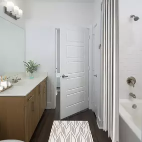 Black granite finishes ensuite bathroom with hardwood-style flooring, white countertops, and natural grain cabinetry