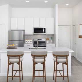 Kitchen with white quartz countertops, white cabinets and gray subway tile backsplash at Camden World Gateway apartments in Orlando, FL