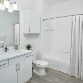 Bathroom with white quartz countertops, white cabinets and bathtub at Camden World Gateway apartments in Orlando, FL