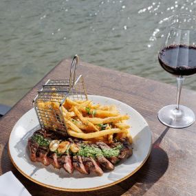 Steak Frites served with a basket of fries next to a window with a view of the Tampa Bay
