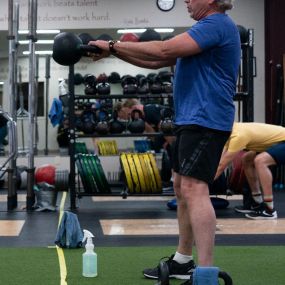 Middle-aged man kettlebell swing in a group training class.