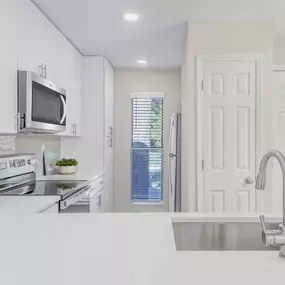 Modern kitchen with white quartz countertops, gray subway tile backsplash, and stainless steel appliances