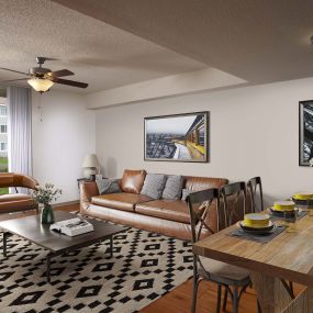 Expansive living room with lighted ceiling fan, wood-look flooring, and private patio in traditional finish style at Camden Doral apartments