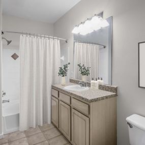 Camden Peachtree City apartments in Peachtree City, GA bathroom with tile, soaking tub, and curved shower rod