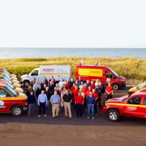 Robies employees in front of trucks at beach with grass and ocean in the background