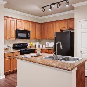 Kitchen wood like flooring and island counter at Camden Woodson Park in Houston, TX