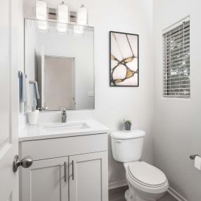 Powder bathroom with white shaker cabinets and white quartz countertops