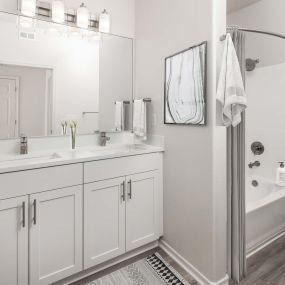 Luxurious main bathroom with dual sink vanity, white quartz countertops, brushed nickel fixtures, and curved shower rod
