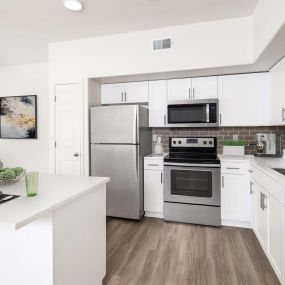 Townhome kitchen with kitchen island, stainless steel appliances, white quartz countertops, subway tile backsplash, and brushed nickel fixtures