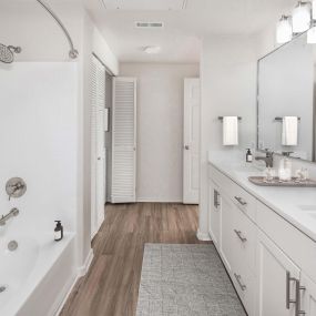 Luxurious bathroom with white quartz countertops, curved shower rod and brushed nickel fixtures