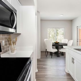 Open concept kitchen with stainless steel appliances, white quartz countertops, subway tile backsplash, and brushed nickel fixtures