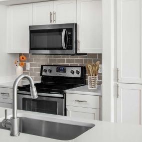 Kitchen with stainless steel appliances, white quartz countertops, subway tile backsplash, and brushed nickel fixtures