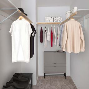 Walk-in closet with wood shelves, rods, and room for dressers