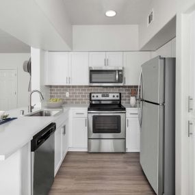 Luxurious kitchen with stainless steel appliances, white quartz countertops, subway tile backsplash, and space for barstool seating