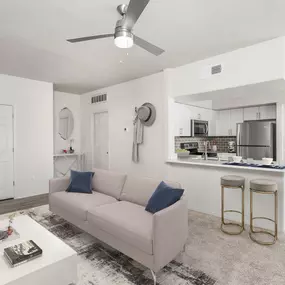 Open concept living room with ceiling fan near kitchen with stainless steel appliances, white quartz countertops, subway tile backsplash, and space for barstool seating