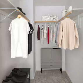 Walk-in closet with wood shelves, rods, and room for dressers