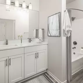 Luxurious main bathroom with dual sink vanity, white quartz countertops, brushed nickel fixtures, and curved shower rod