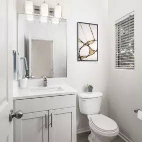 Powder bathroom with white shaker cabinets and white quartz countertops