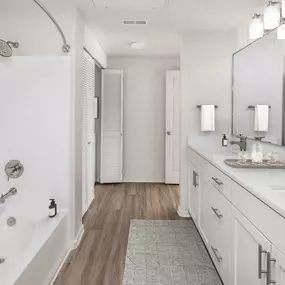 Luxurious bathroom with white quartz countertops, curved shower rod and brushed nickel fixtures