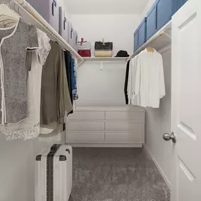 Walk-in closet with wooden shelves, rods and room for a dresser