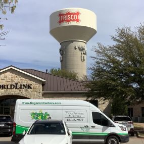 One of the Tioga Plumbing & Electric vans in front of WorldLink and a water tower in Frisco Texas.