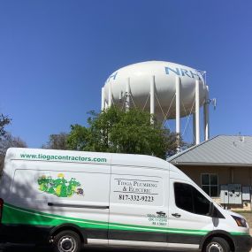 The Tioga service van in front of a NRH water tower in North Richland Hills Texas.