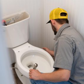 A skilled plumber from Tioga Contractors fixing a toilet in the Euless, TX area.