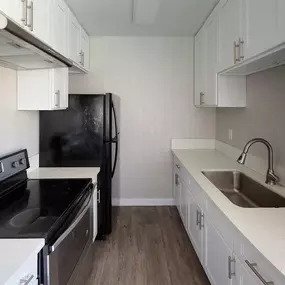 Kitchen With White Cabinetry And Black Appliances