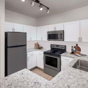 Kitchen with white cabinetry, quartz countertops, and stainless steel appliances