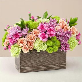 Capture the beauty of the seasons in bloom with our Simple Charm Bouquet. Gorgeous blooms such as peach spray roses, green button pompon, pink mini carnations and lavender cushion pompons fill a weathered wooden box with freshness.