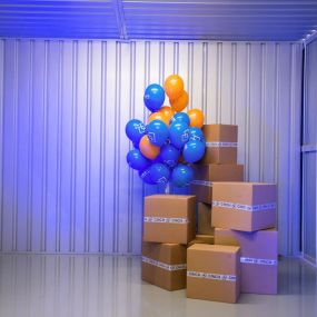 Boxes stacked in a storage unit with balloons - Cinch Self Storage