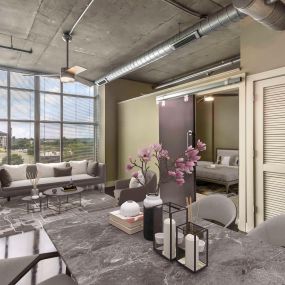 Open concept living and dining room with barn door to bedroom and concrete flooring