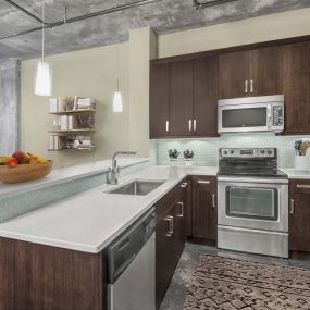 Kitchen with glass cooktop two tier quartz countertops and tile backsplash