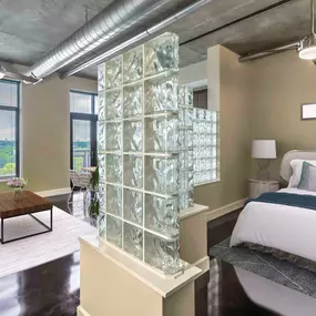 Open concept studio floor plan bedroom and living area with exposed ductwork and concrete flooring