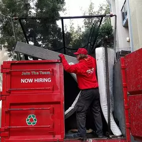 Junk King team member fits one more mattress into our BIG RED truck from an apartment junk removal job.