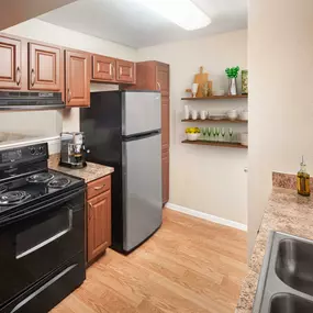 Kitchen with black appliances wood look flooring chestnut cabinets and laminate countertops