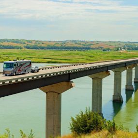 A photo of an RV with Blue Ox trailer hitch flat towing across a bridge