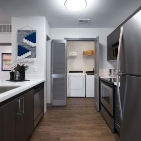 Modern style kitchen with stainless steel appliances and white countertops and full size washer and dryer