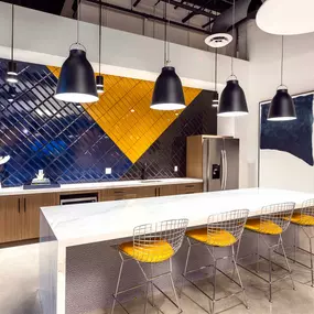 Resident lounge kitchen with barstool seating and white quartz countertops and blue subway tile backsplash