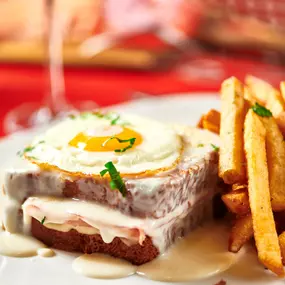 Croque Madame - griddled bistro ham & gruyere on brioche topped with mornay and a sunnyside up egg, chips