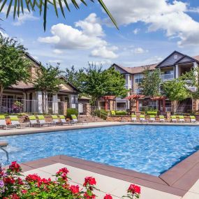 Expansive pool with palm trees, flowers, and lounge chairs at Camden Asbury Village in Raleigh, NC.